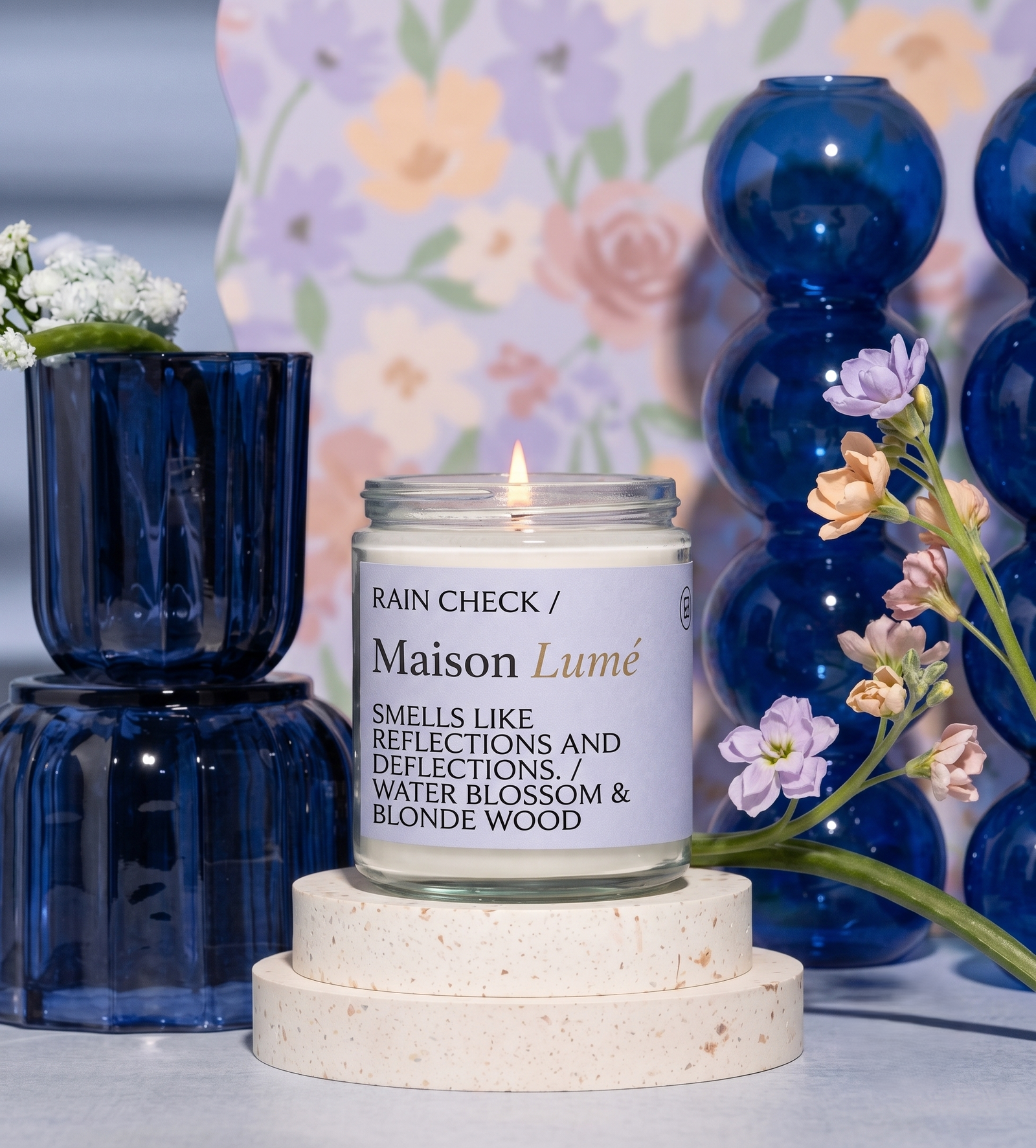 Close up of a hand-poured candle beside blue glassware